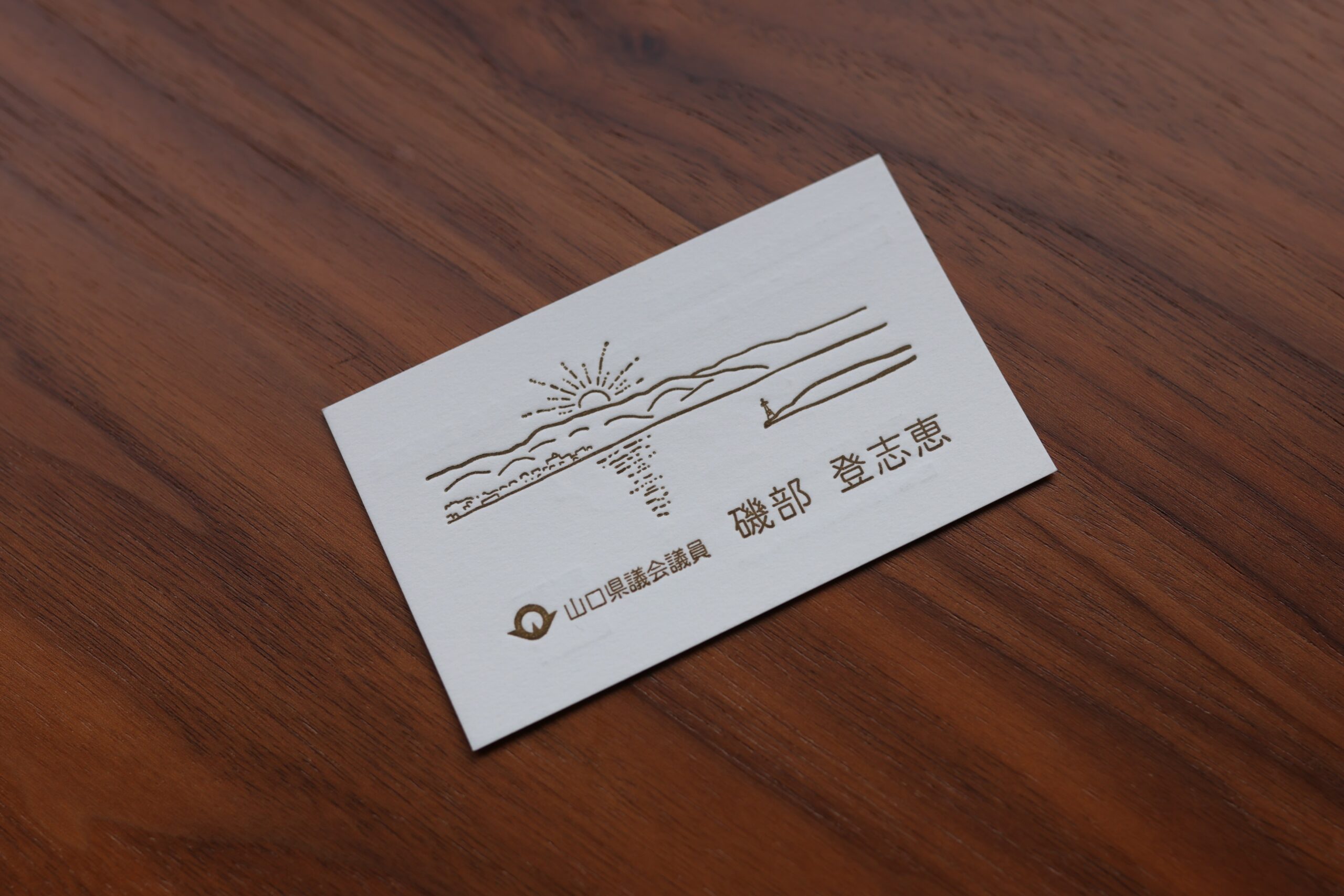 山口県議会議員・磯部登志恵様の名刺。海と朝日を描いた繊細な線画と文字を落ち着いた色で印刷した表面