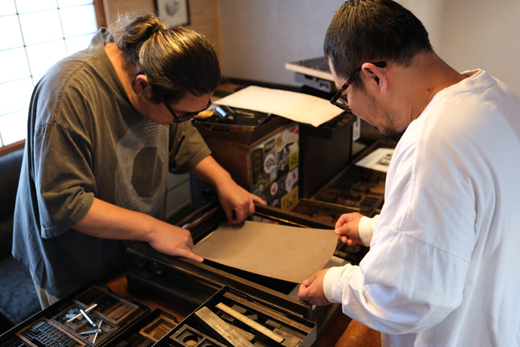 NINE LETTERPRESSの活版印刷ワークショップで、2人が校正用印刷機に紙をセットしている様子